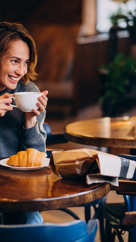 a woman sitting at a table with a cup of coffee at The Tupelo