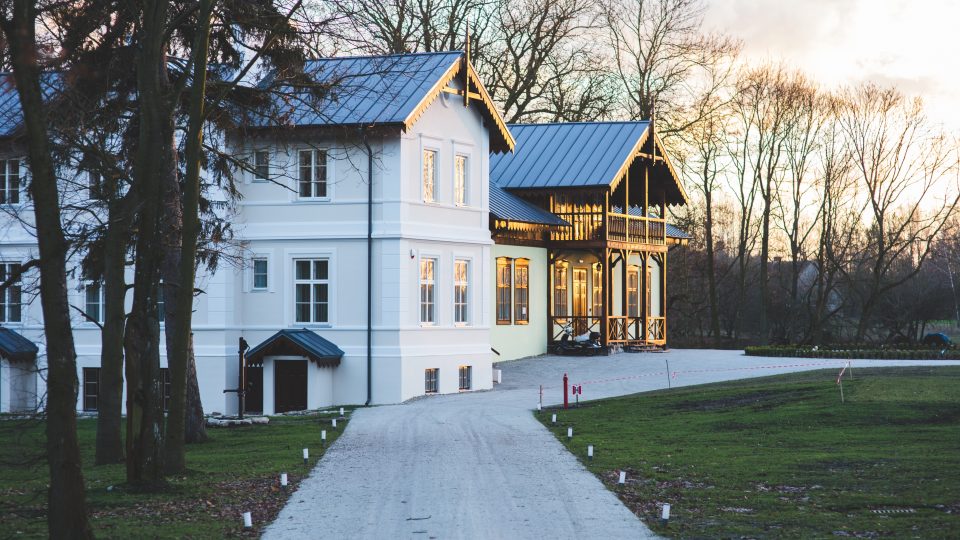 a large white house with a driveway and trees at The Tupelo