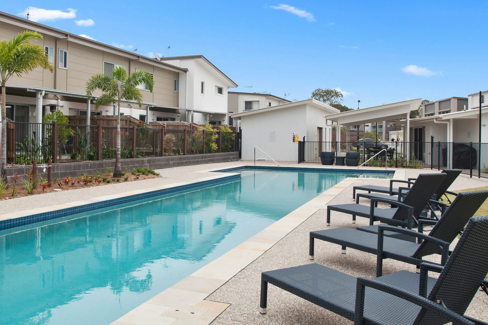 a pool with lounge chairs and a fence around it at The Tupelo