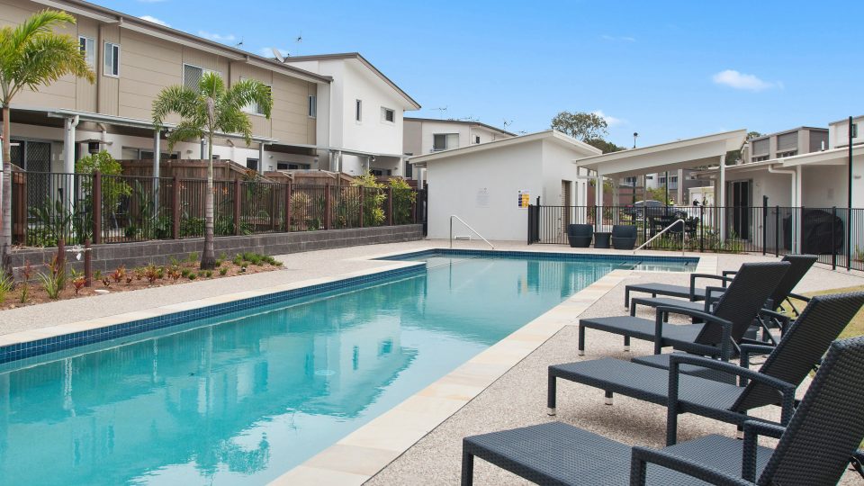 a pool with lounge chairs and a fence around it at The Tupelo